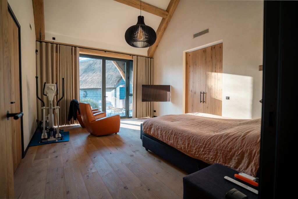 Moderne slaapkamer met bed, fiets en terraszicht.