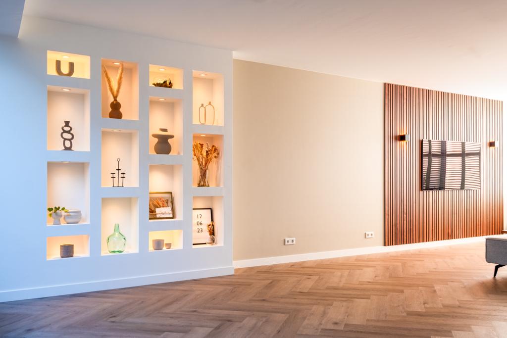 Moderne woonkamer met verlichte wandplanken en houten panelen.