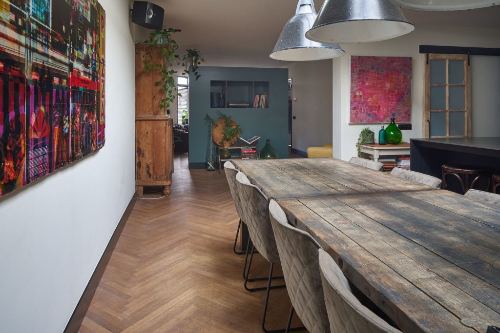 Eetkamer met houten tafel en kunst aan de muur.