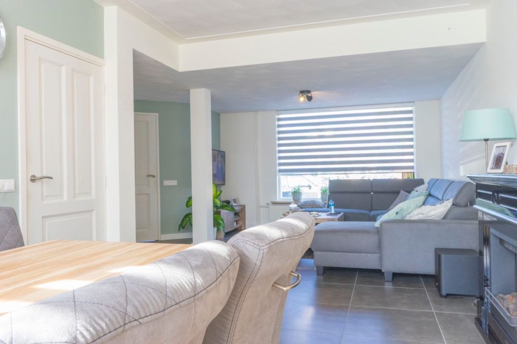 Moderne woonkamer met grijze bank en grote ramen.