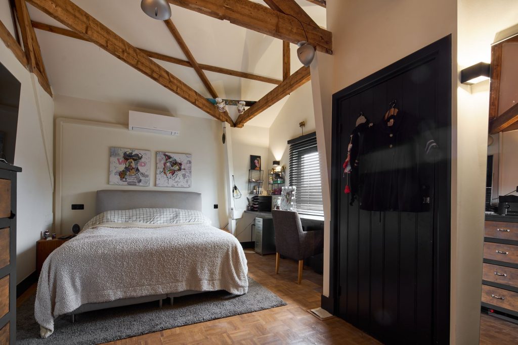 Gezellige slaapkamer met houten balken en modern meubilair.