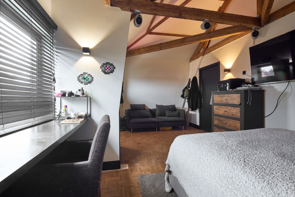 Gezellige slaapkamer met bureau, bank en kast.