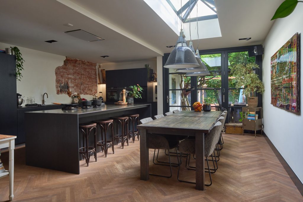 Stijlvolle keuken met houten vloer en grote eettafel.