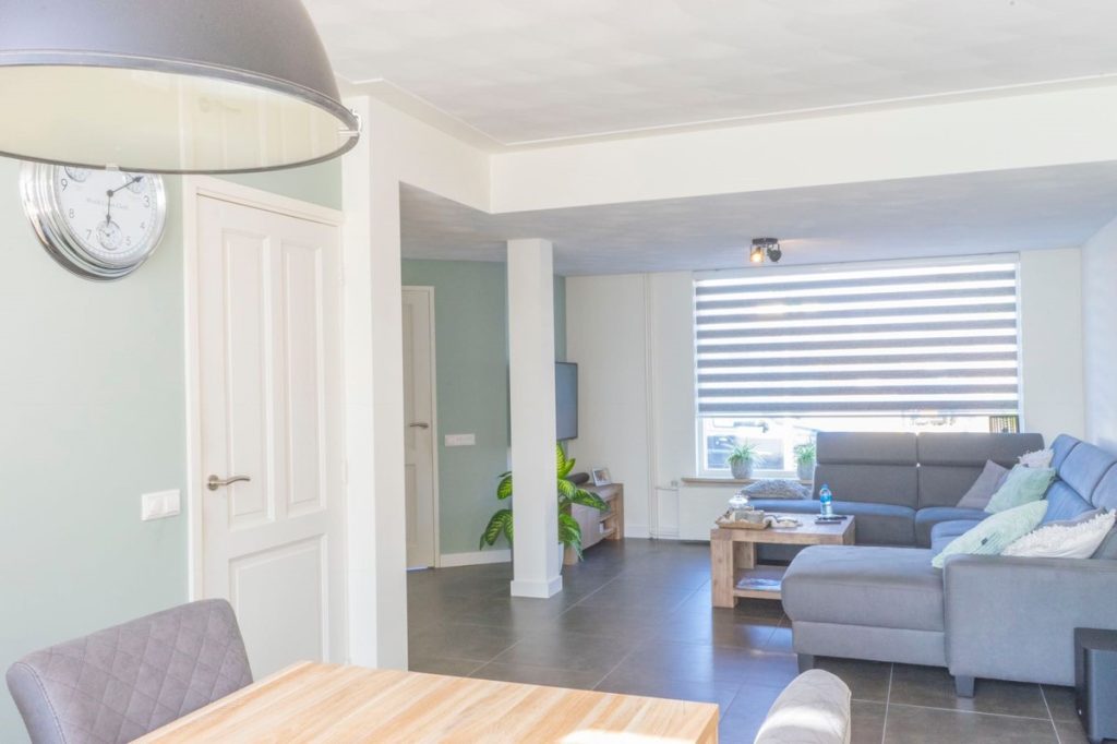 Moderne woonkamer met grijze bank en houten tafel.