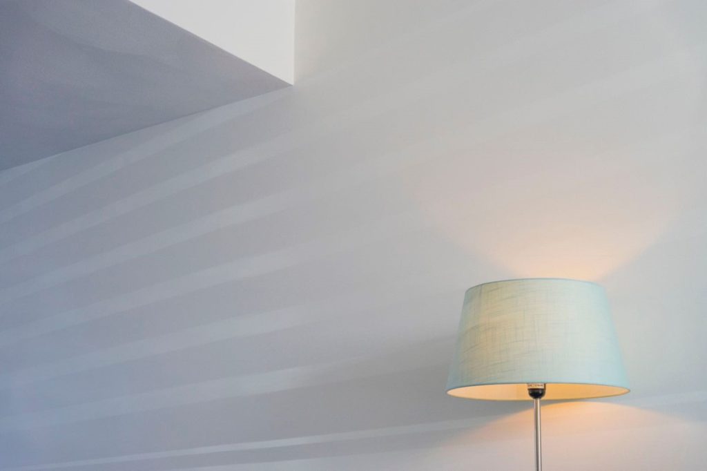 Moderne hoeklamp straalt zacht licht uit op muur.