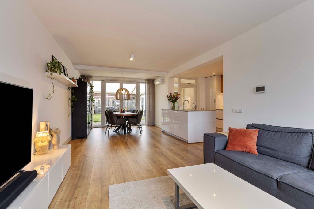 Modern living room with kitchen and large windows.
