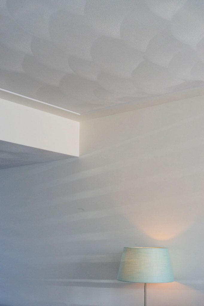 Verlichte lamp in hoek van geverfde kamer.