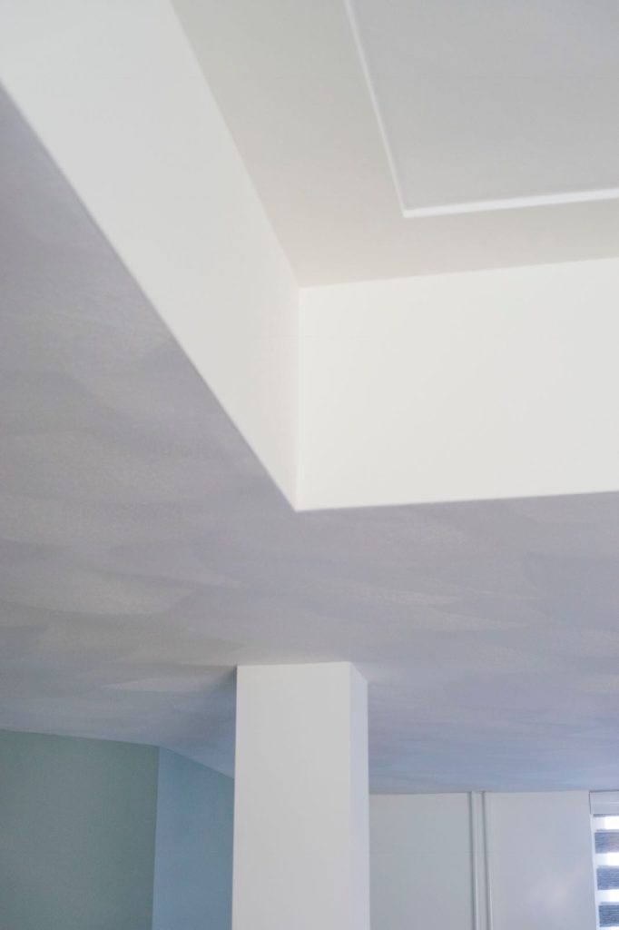 Wit geschilderde binnenhoek van plafond en muur.