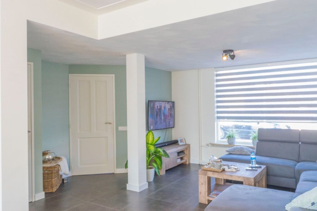 Moderne woonkamer met grijze bank en tv aan muur.