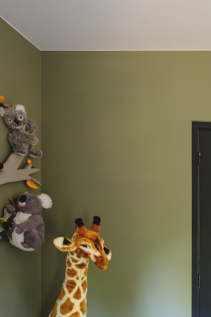 Knuffeldieren in kinderkamer met groene muur.