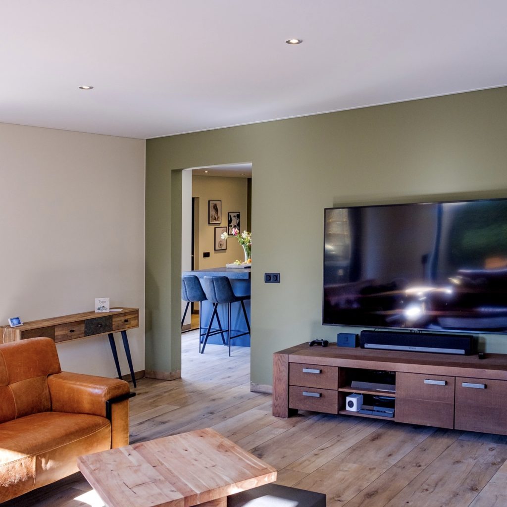 Moderne woonkamer met flatscreen-tv en leren stoel.
