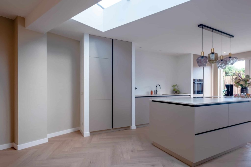 Moderne keuken met kookeiland en hanglampen.