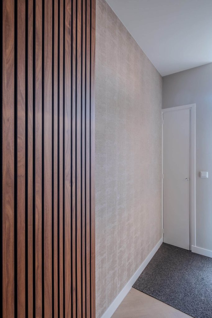 Hal met houten panelen en witte deur.