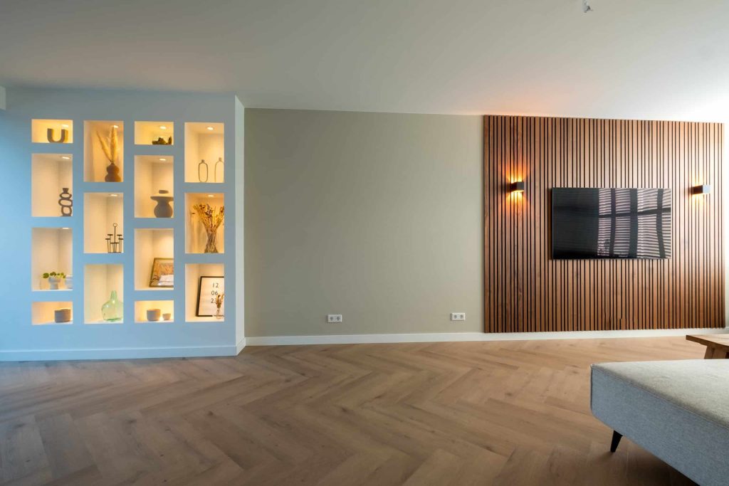 Moderne woonkamer met nisverlichting en houten wanddecor.