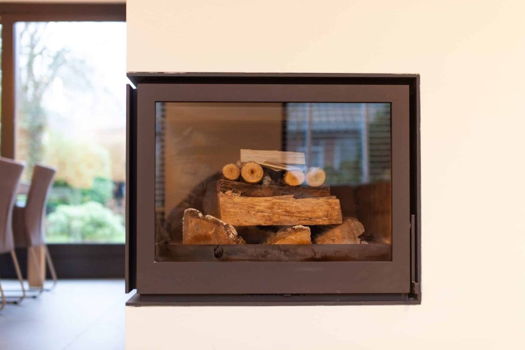 Ingebouwde haard met houtblokken in moderne woonkamer.