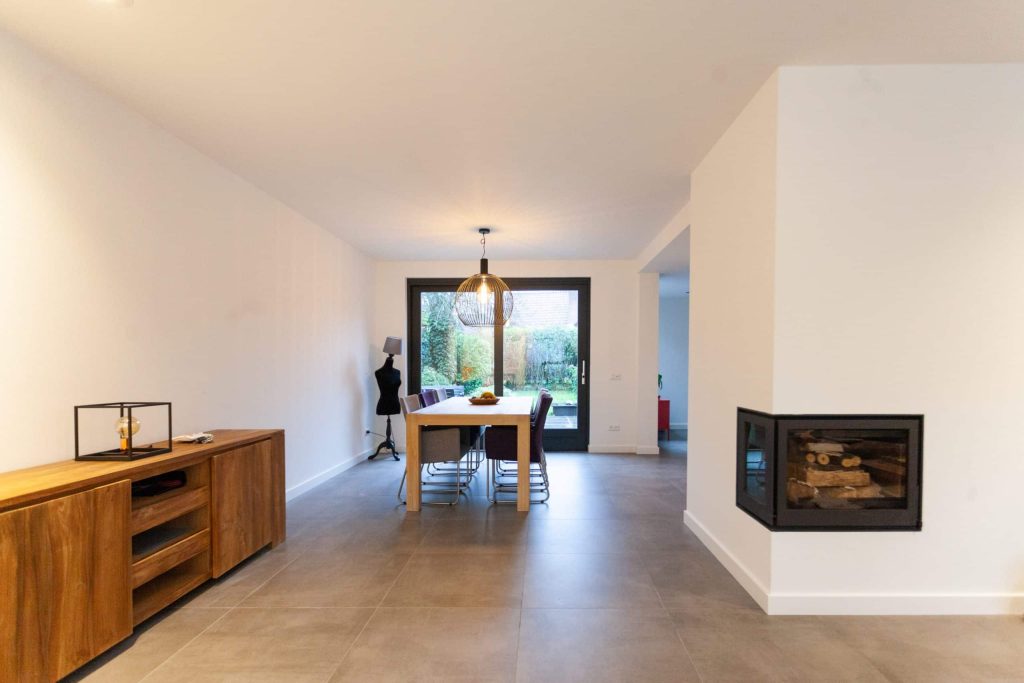 Moderne eetkamer met grote glazen deur.