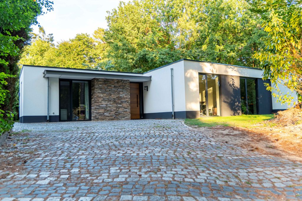 Modern bungalow with driveway and green surroundings