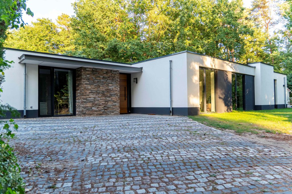 Moderne bungalow met stenen muur en oprit.