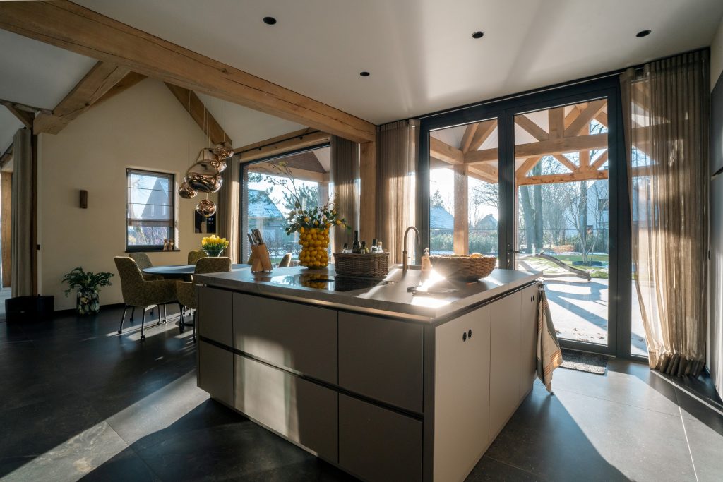 Lichte moderne keuken met groot eiland en glazen deuren.