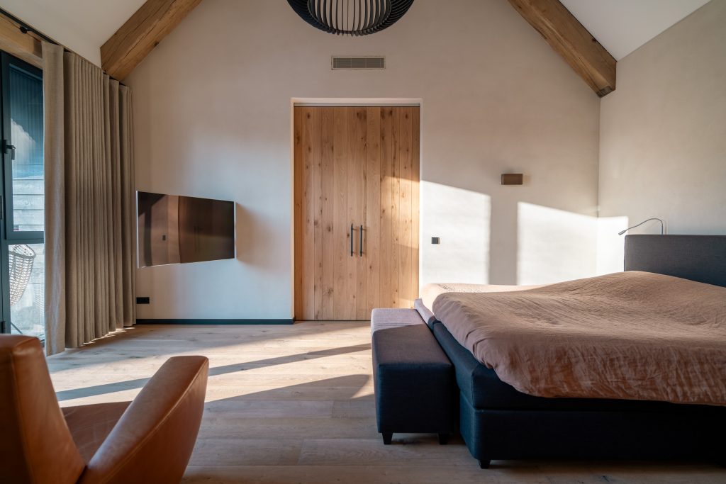 Modern bedroom with bed, TV and wooden door