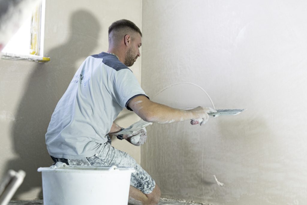 Stukadoor werkt muur glad met pleister.
