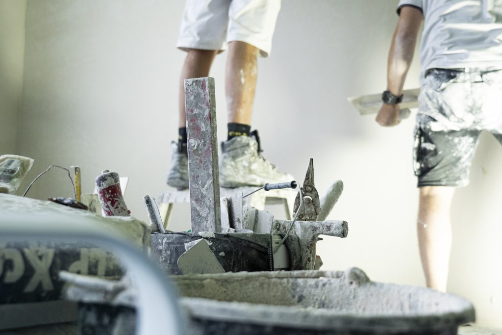 Bouwvakkers met bouwmaterialen in een stoffige omgeving.
