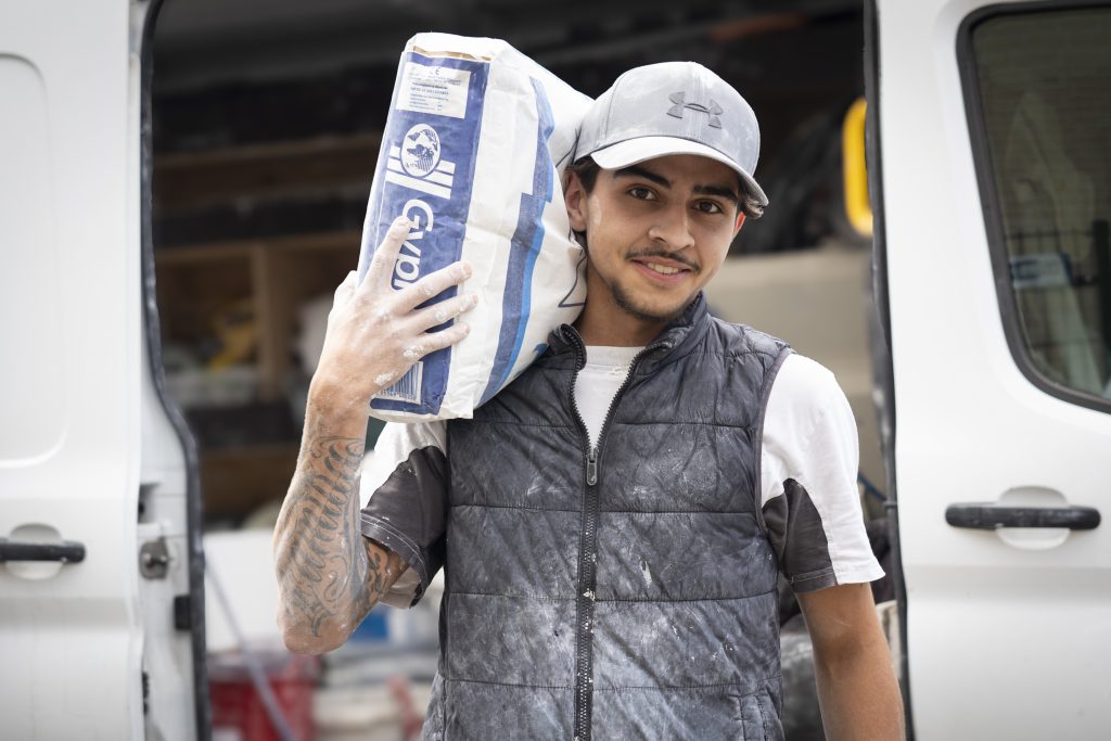 Man draagt cementzak bij bestelwagen.