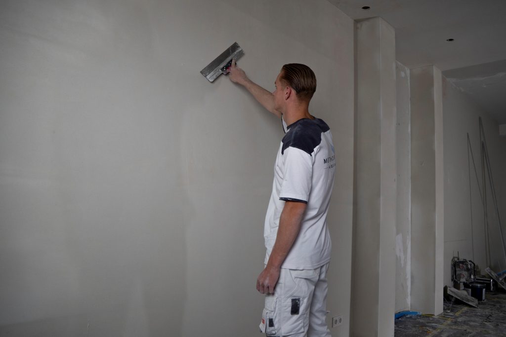 Man pleistert een muur in een kamer