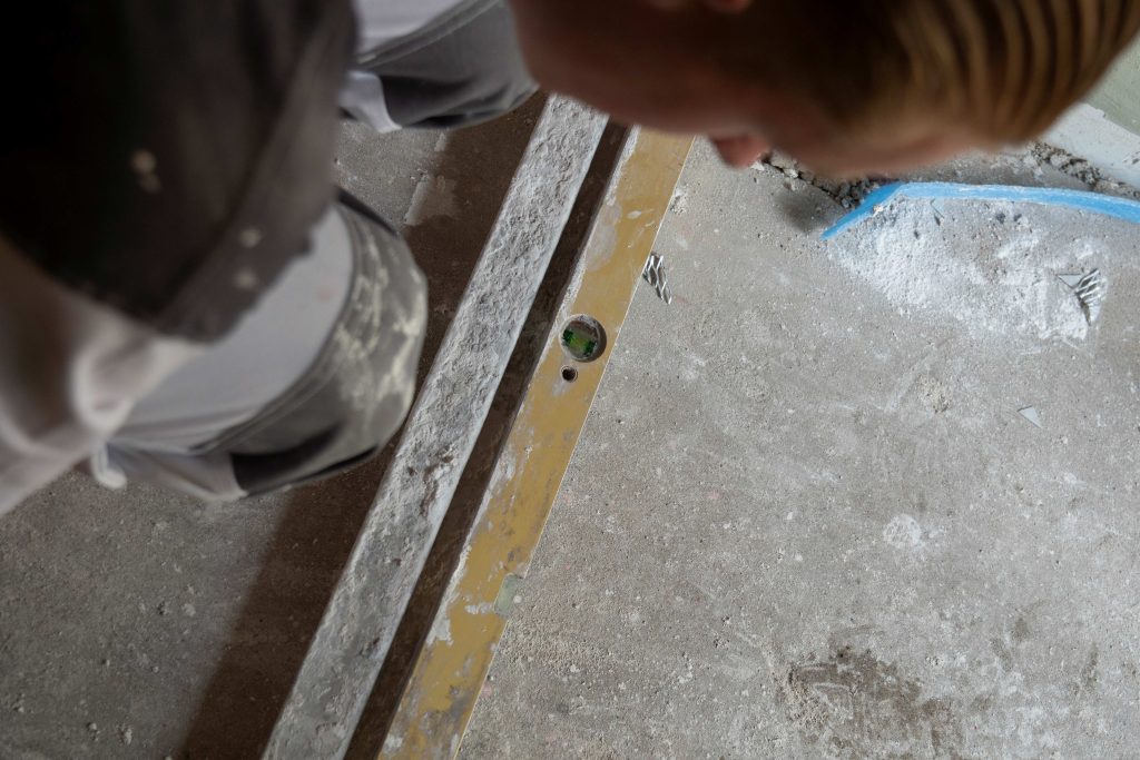 Vrouw controleert waterpas op ruwe vloer.